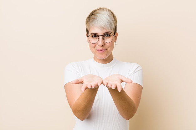 Joven auténtica mujer natural con una camisa blanca sosteniendo algo con palmeras