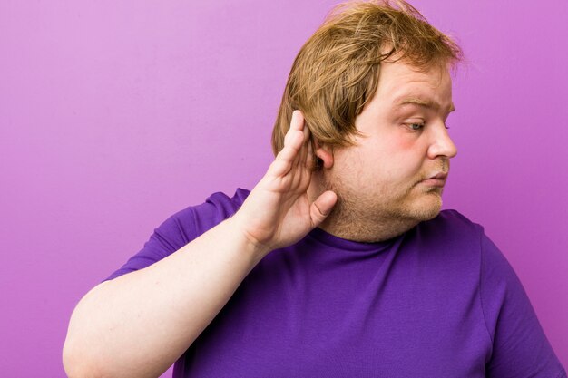 Joven auténtico pelirrojo gordo tratando de escuchar un chisme.