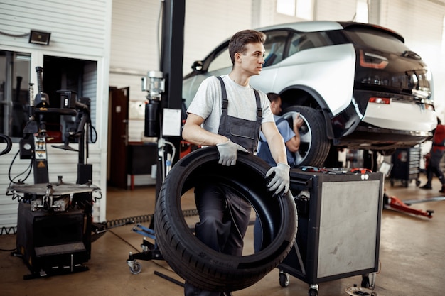 Un joven automecánico con guantes y uniforme está trabajando.