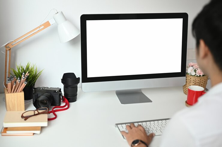 Foto un joven autónomo está trabajando con una computadora de pantalla blanca en la oficina
