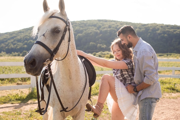 El joven ayuda a su esposa a subirse a un caballo