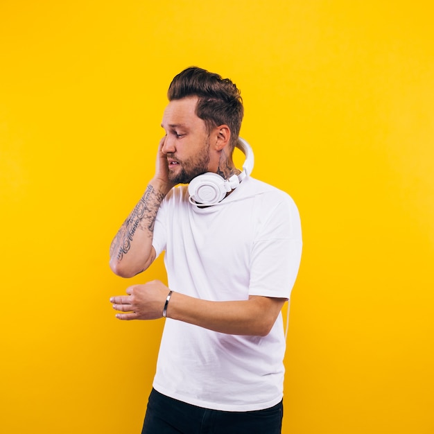 Joven bailando y escuchando música. emociones, expresiones faciales, sentimientos, lenguaje corporal, signos. imagen sobre un fondo amarillo de estudio.