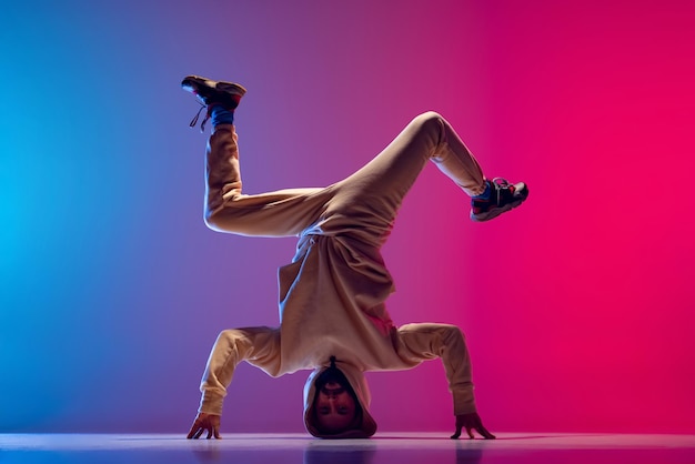 Foto joven bailando hiphop breakdance aislado sobre fondo rosa azul degradado