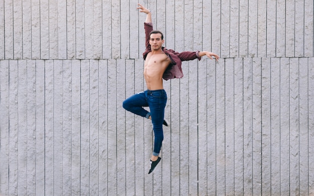 Joven bailarín realizando un salto en ropa jean