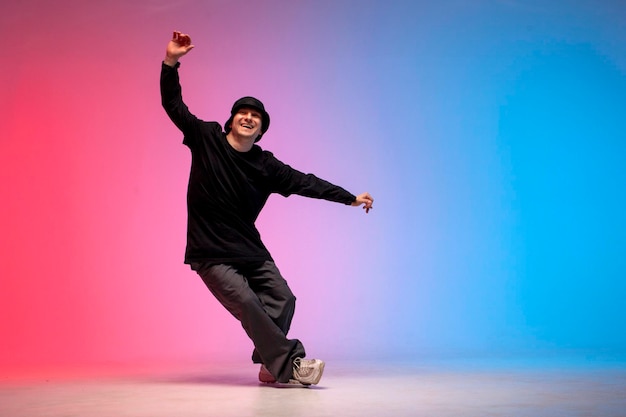 Un joven bailarín con ropa negra rompe el baile con luces de neón y un hombre realiza un movimiento de hip hop