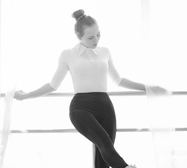 Joven bailarina de ballet en un calentamiento La bailarina se prepara para actuar en el estudio Una chica con ropa y zapatos de ballet amasa junto a los pasamanos