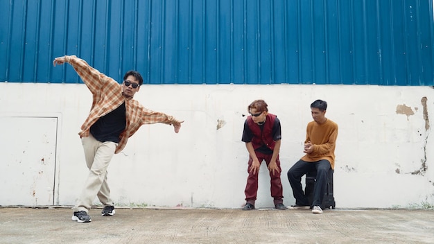 Foto joven bailarina callejera bailando al estilo hip hop con un amigo animando detrás de endeavor