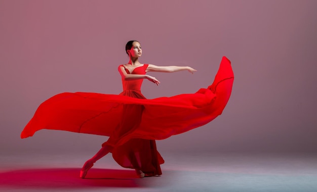 Una joven bailarina elegante vestida con zapatos de punta y una falda roja ingrávida demuestra sus habilidades de baile La belleza del ballet clásico