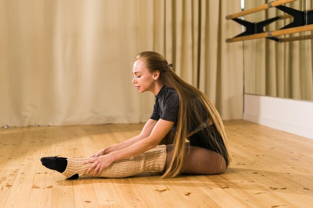 Joven bailarina estirándose y entrenando en barre en un estudio de baile ballet y concepto de bailarina