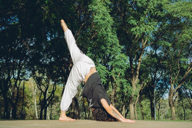 Joven bailarina latina estirándose para hacer danza contemporánea afuera en un parque