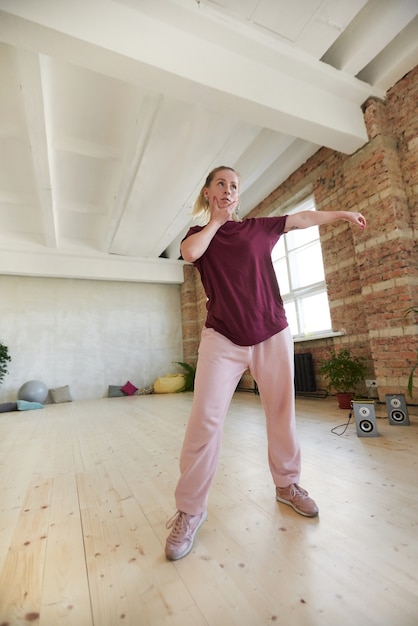 Foto joven bailarina mostrando el movimiento y bailando con música en el estudio de danza