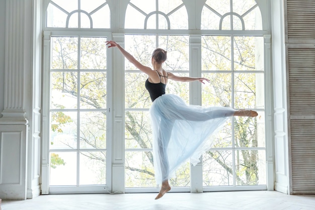 Joven bailarina practicando posiciones de ballet en estudio