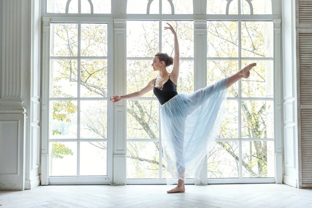 Joven bailarina practicando posiciones de ballet en estudio