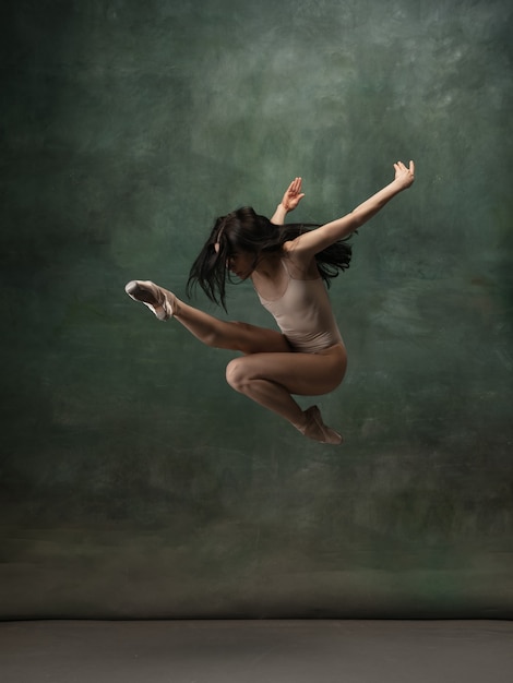 Joven bailarina tierna agraciada sobre fondo de estudio verde oscuro