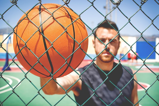 joven con el baloncesto detrás de una valla