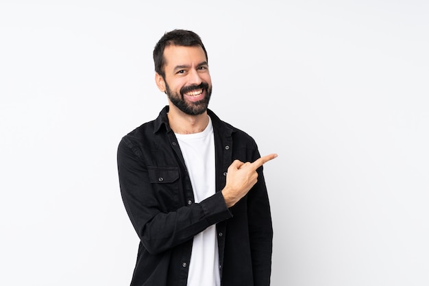 Joven con barba apuntando hacia un lado para presentar un producto