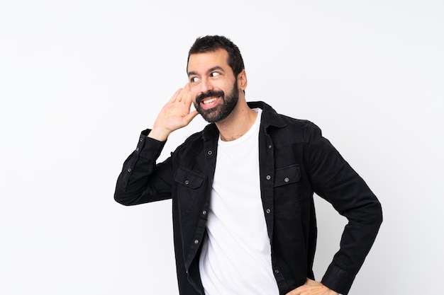 Joven con barba escuchando algo poniendo la mano en la oreja