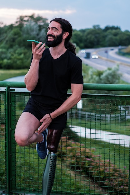 Joven con barba larga hablando por teléfono inteligente al aire libre