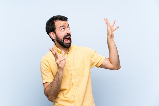 Joven con barba sobre azul aislado nervioso y asustado