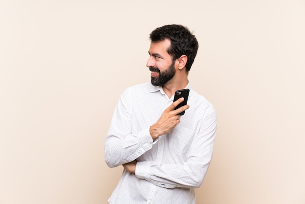 Joven con barba sosteniendo un móvil mirando hacia el lado