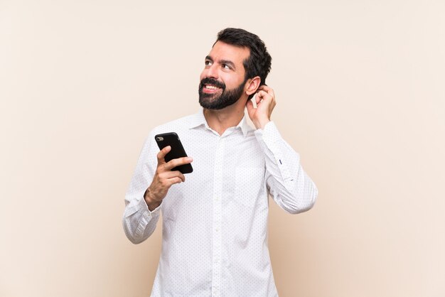 Joven con barba sosteniendo un móvil pensando en una idea