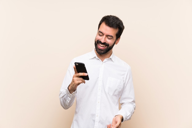 Joven con barba sosteniendo un móvil sonriendo