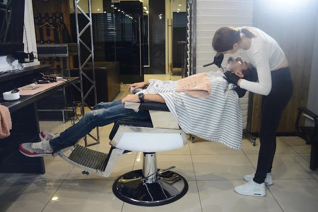 Una joven barbero se afeita la barba, el hombre de la peluquería