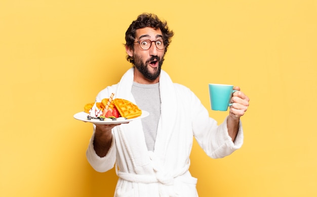 Joven barbudo en bata de baño y desayunando