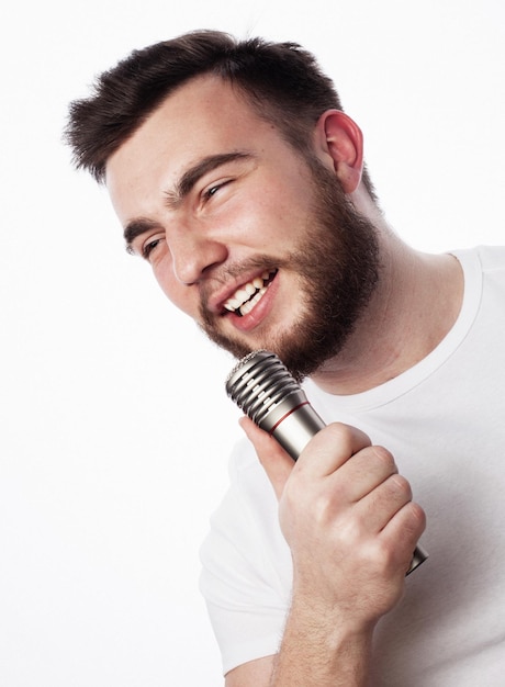 Joven barbudo con camisa blanca cantando en el micrófono