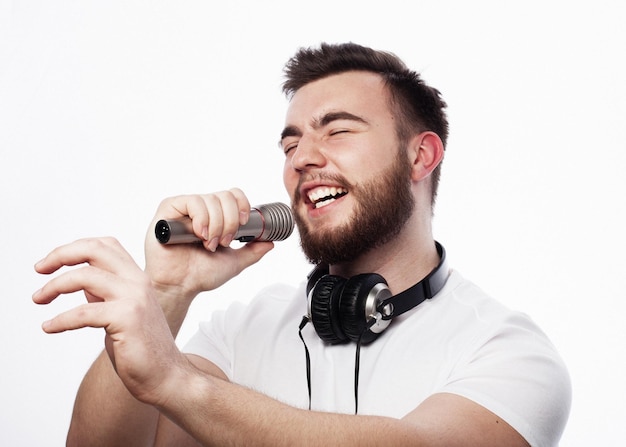 Joven barbudo con camisa blanca cantando en el micrófono