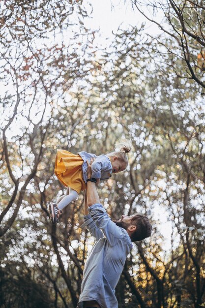 joven barbudo con estilo caminando en el parque de otoño junto con su dulce hija