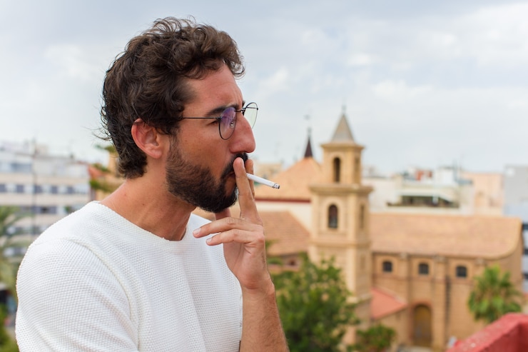 Foto joven barbudo fumando un cigarrillo