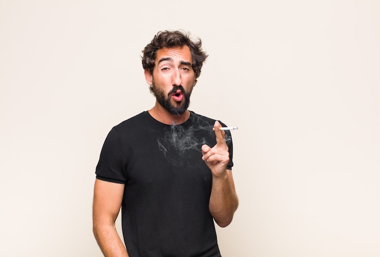 Foto joven barbudo fumando un cigarrillo