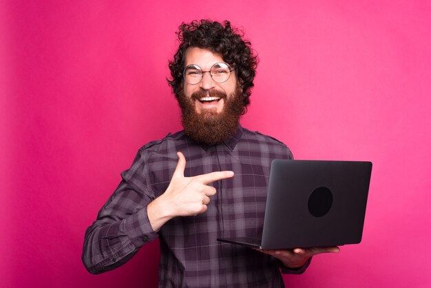 Joven barbudo con gafas sosteniendo portátil