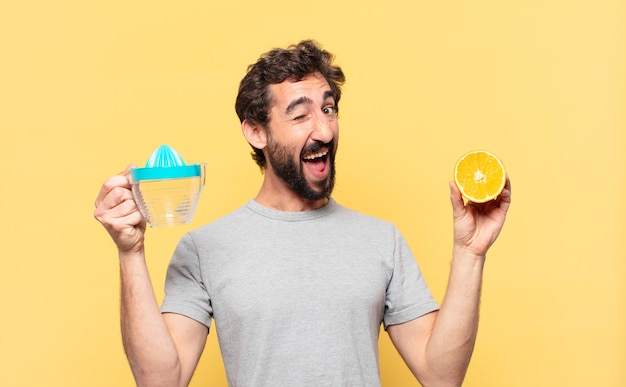 Joven barbudo haciendo dieta expresión feliz y sosteniendo una naranja