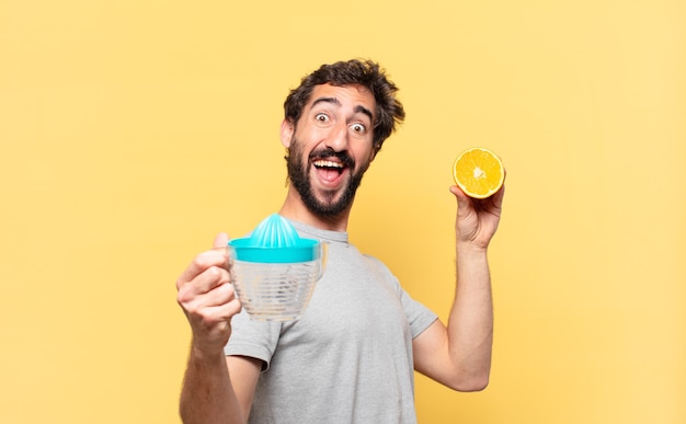 Joven barbudo haciendo dieta expresión de sorpresa y sosteniendo una naranja