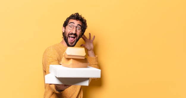 Joven barbudo loco habiendo comida rápida para llevar con un espacio de copia