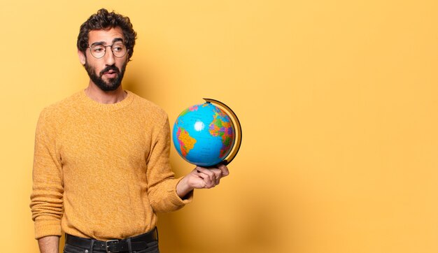 Joven barbudo loco sosteniendo un mapa del mundo.