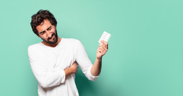 Joven barbudo loco con una tableta de pastillas