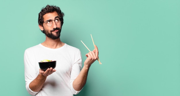 Joven barbudo loco con un tazón de ramen de fideos