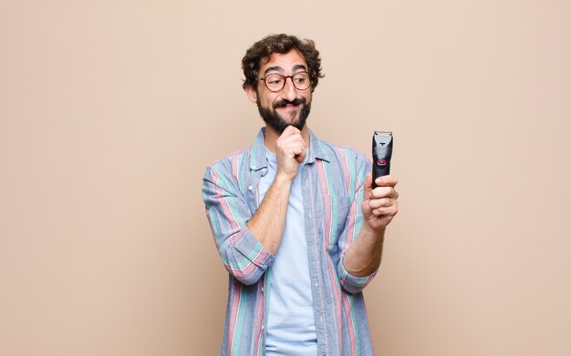 Joven barbudo con una maquinilla de afeitar eléctrica