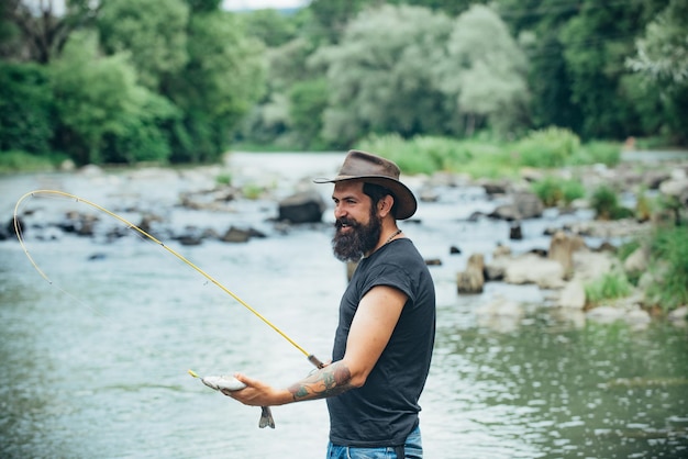 Joven barbudo pescando en un lago o río pescando con mosca hipster barbudo pescando truchas