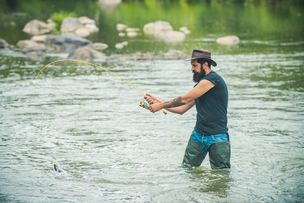 Joven barbudo pescando en un lago o río