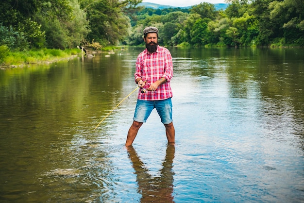 Joven barbudo pescando en un lago o río