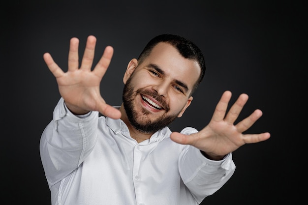 Joven barbudo de pie con los brazos levantados