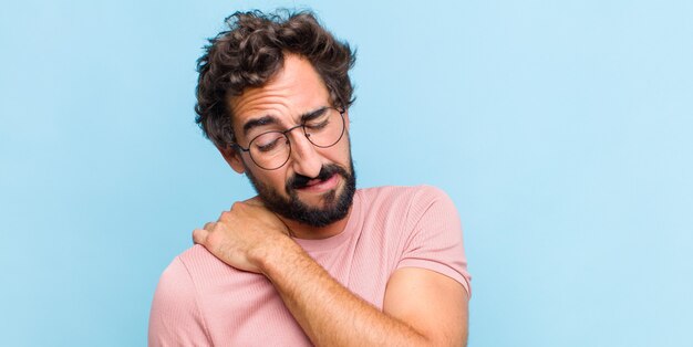 Joven barbudo que se siente cansado, estresado, ansioso, frustrado y deprimido, que sufre de dolor de espalda o cuello