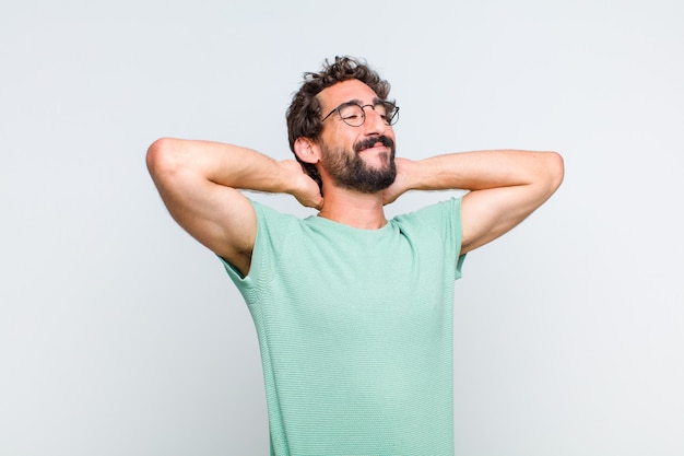 Joven barbudo sonriendo y sintiéndose relajado, satisfecho y despreocupado, riendo positivamente y escalofriante