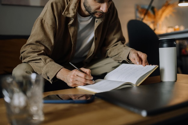 Foto joven barbudo tomando notas en la oficina en casa, retrato.