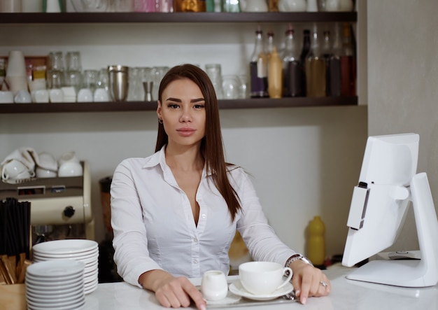 Un joven barista en el bar sirve café en una bandeja.