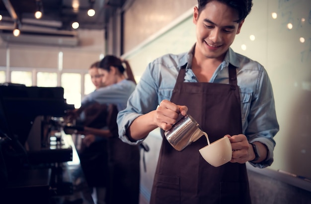 Joven barista experto en la elaboración de café campeón creando arte latte en una taza de café para un cliente